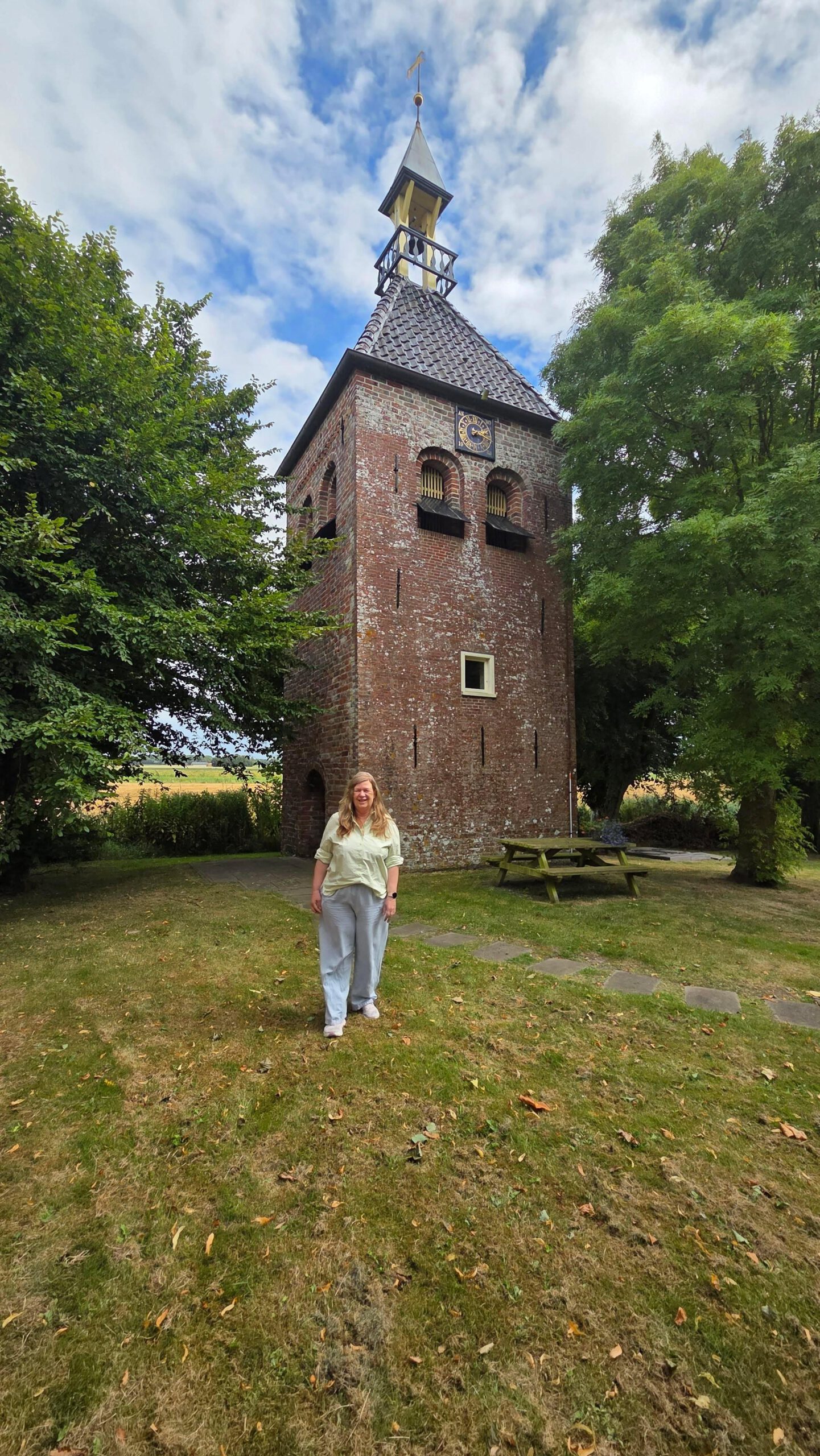 Gea Kramer bij de losse kerktoren van Den Andel op het Hogeland
